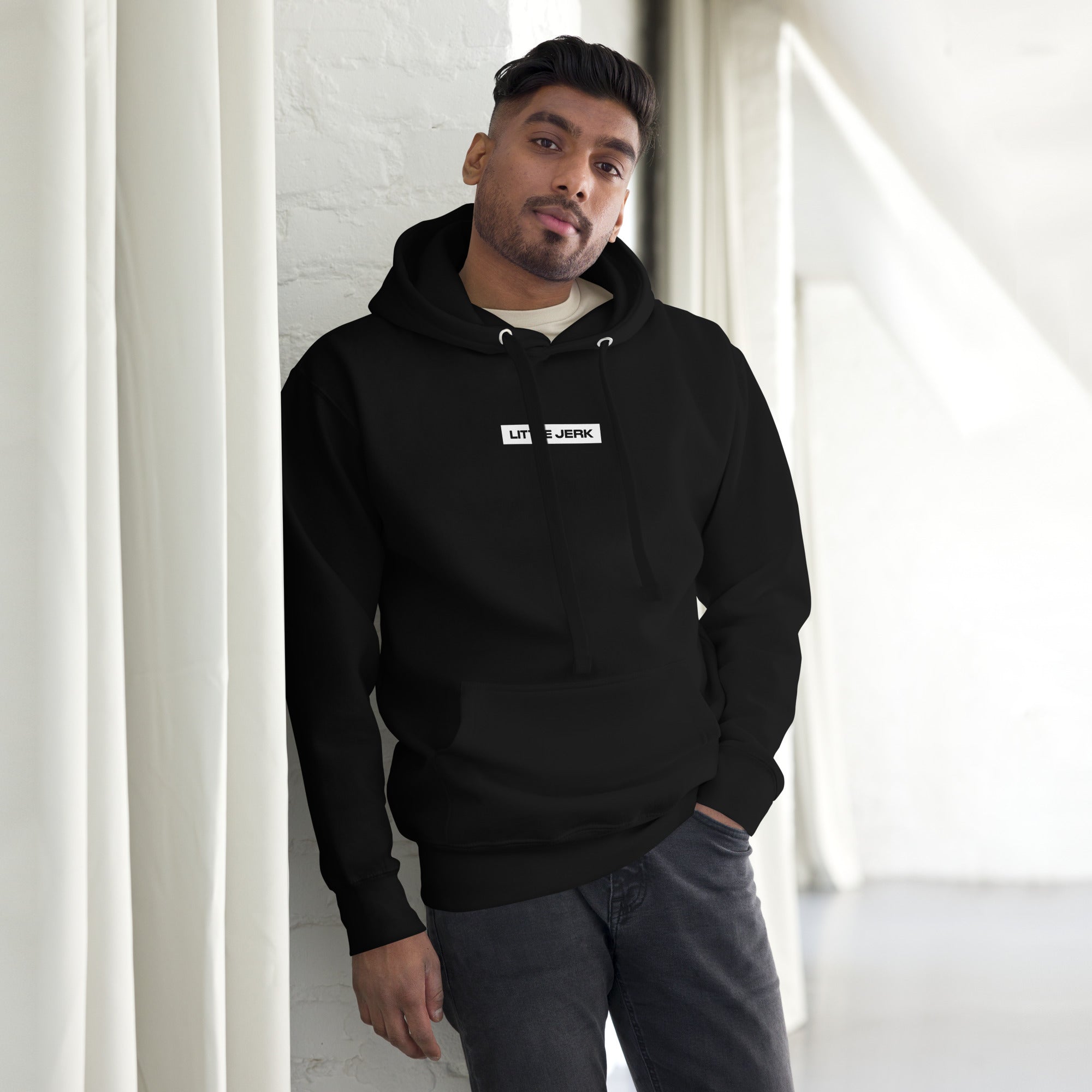 Person in a black hoodie leaning against a wall
